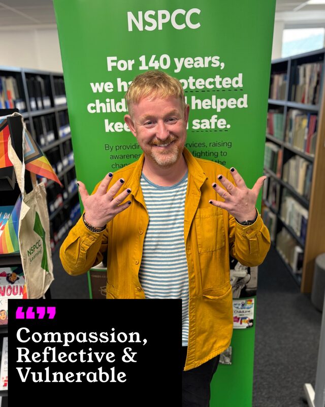 Chris Sherwood holding up his painted nails. His three words: Compassion, Reflective and Vulnerable.