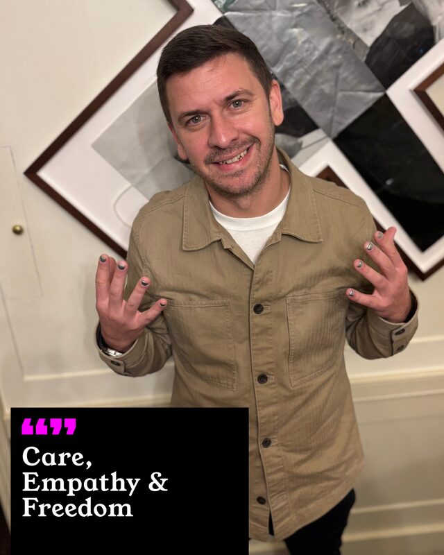 Danny Weitzkorn holding up his painted nails. His three words: Care, Empathy and Freedom.