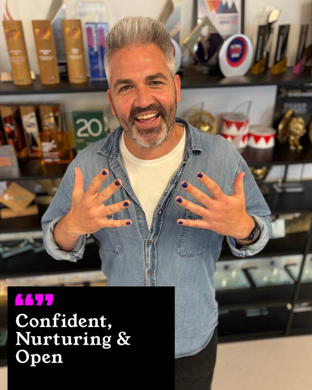 Dave Lowe holding up his painted nails. His three words: Confident, Nurturing and Open.