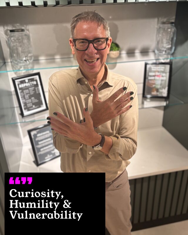 Robert Baker holding up his painted nails. His three words: Curiosity, Humility and Vulnerability.