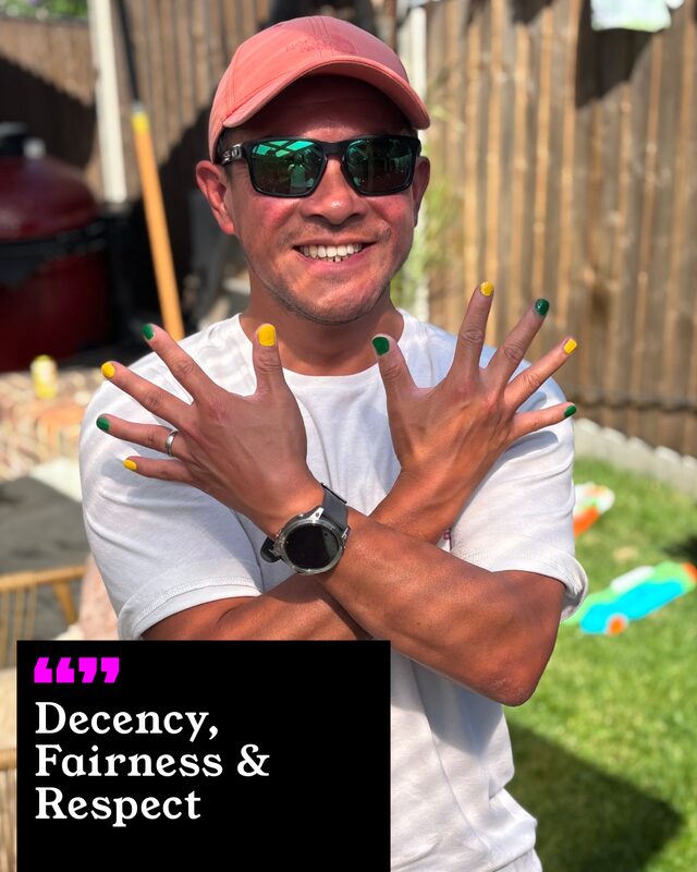 Tommy Wong holding up his painted nails. His three words: Decency, Fairness and Respect.