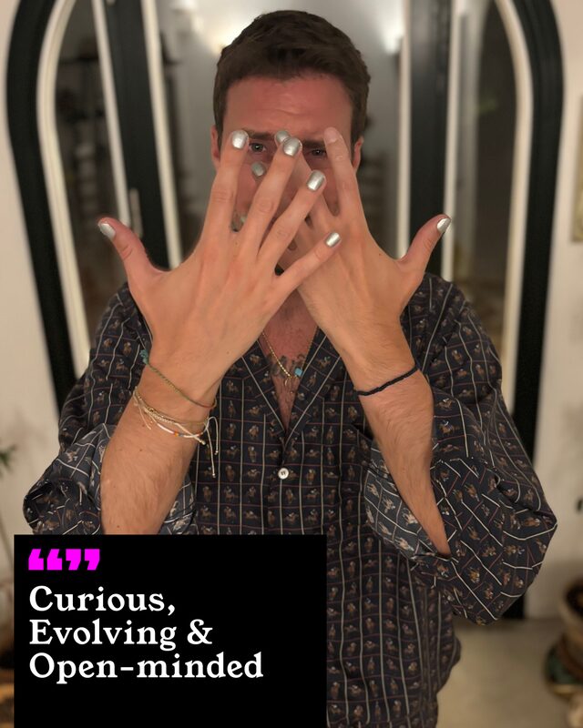 Victor Hyll holding up his painted nails. His three words: Curious, Evolving and Open-minded.