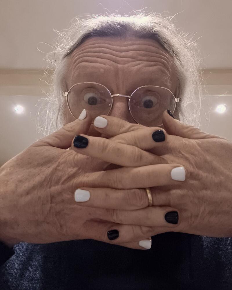 Old, weathered hands with black and white painted nails
